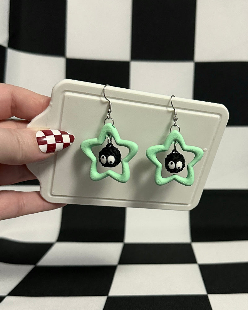 Star-shaped earrings on a card held against a checkered background