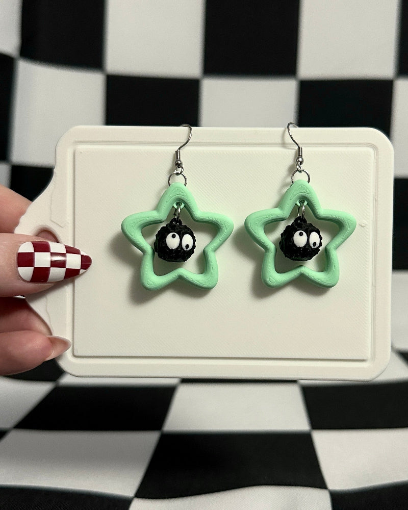 Star-shaped earrings with black eyes on a checkered background