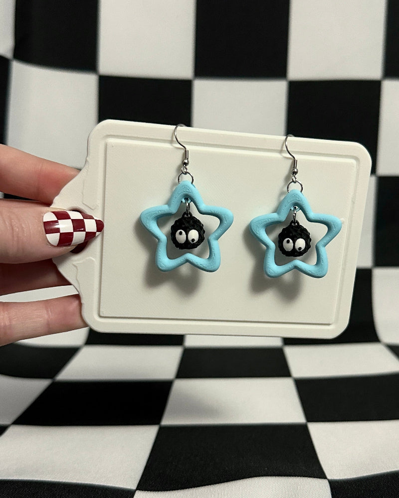 Star-shaped earrings with black centers on a checkered background