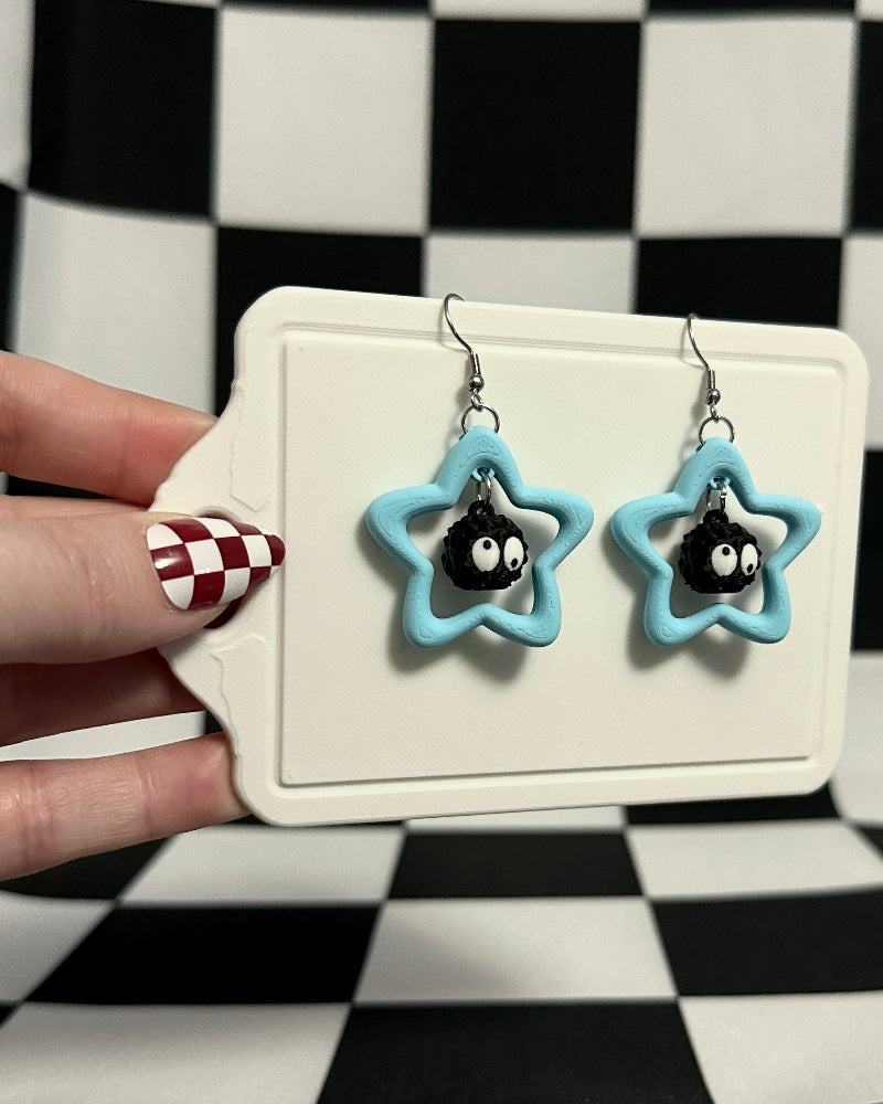Star-shaped earrings on a card held against a checkered background