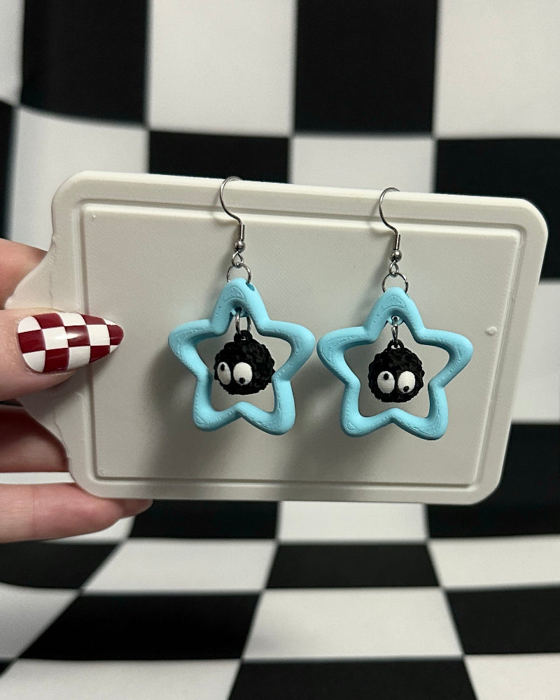 Star-shaped earrings with black centers held on a checkered background