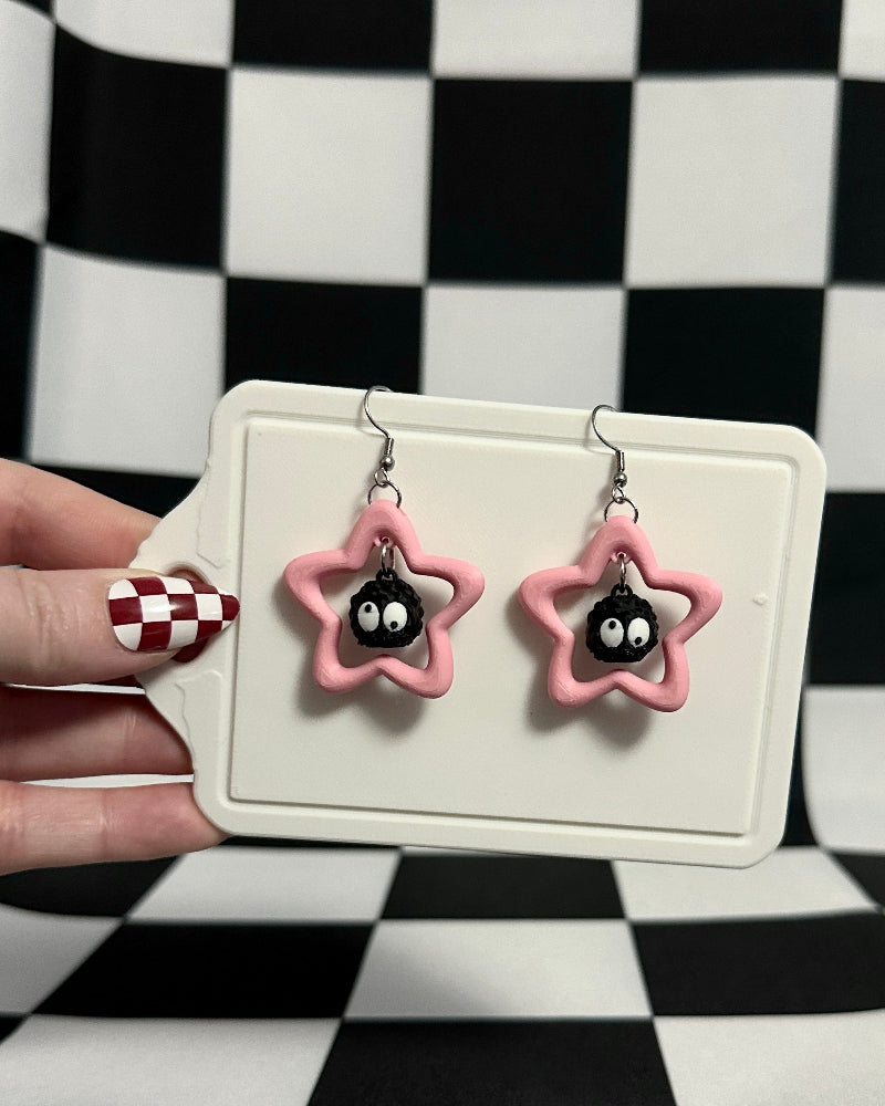 Star-shaped earrings with black centers held on a checkered background