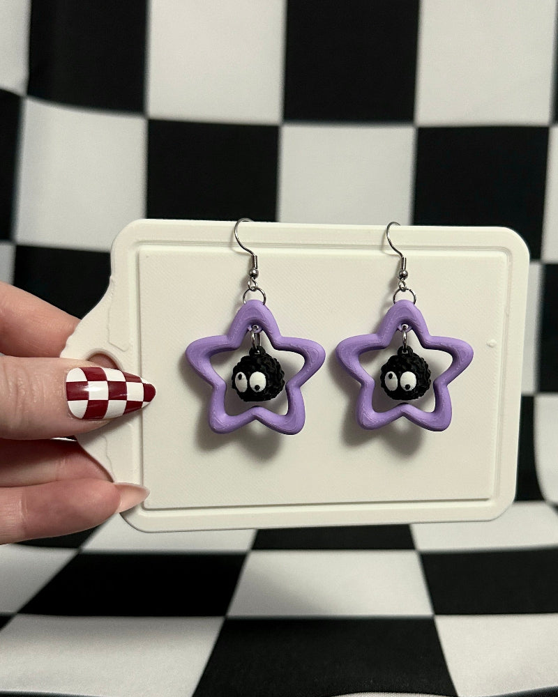 Star-shaped earrings with purple accents on a checkered background
