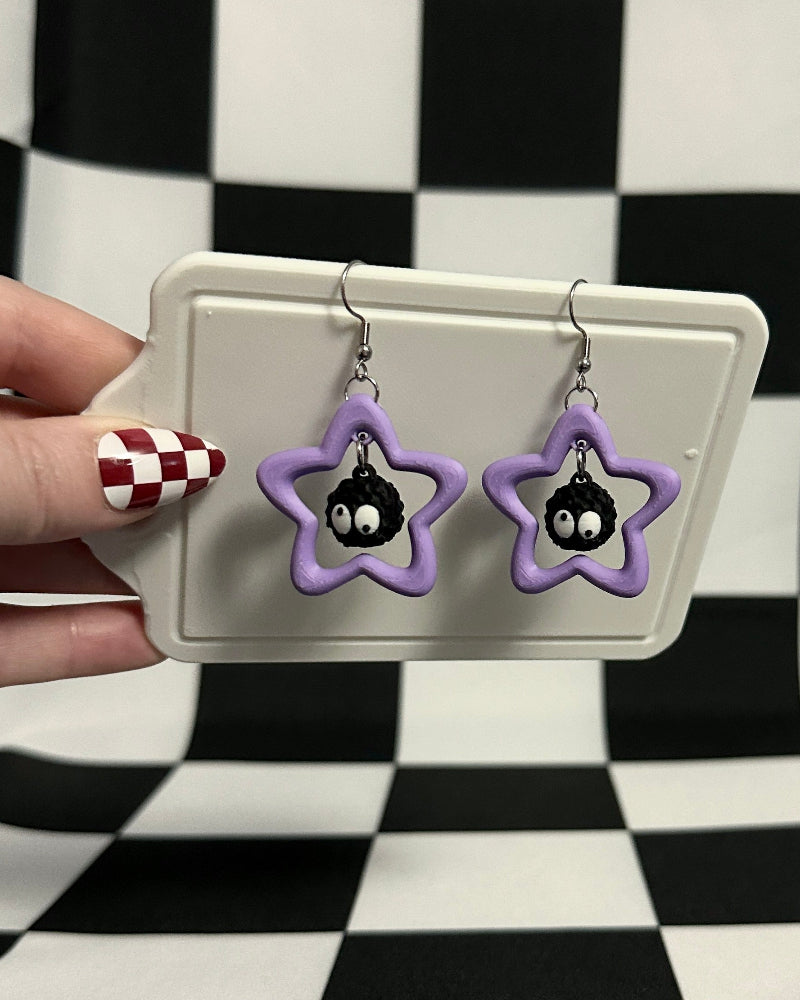 Star-shaped earrings on a card held against a checkered background