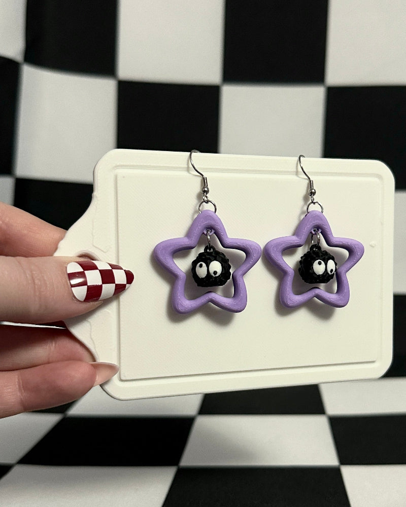 Star-shaped earrings on a card held against a checkered background