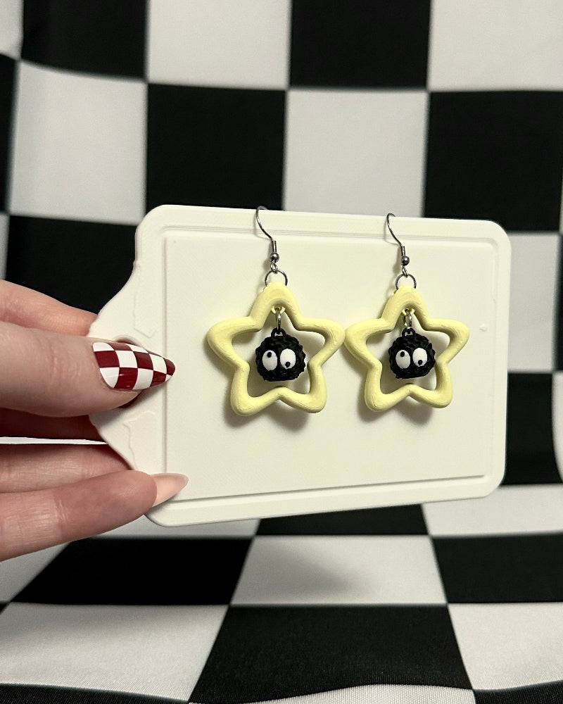 Star-shaped earrings on a card held against a checkered background