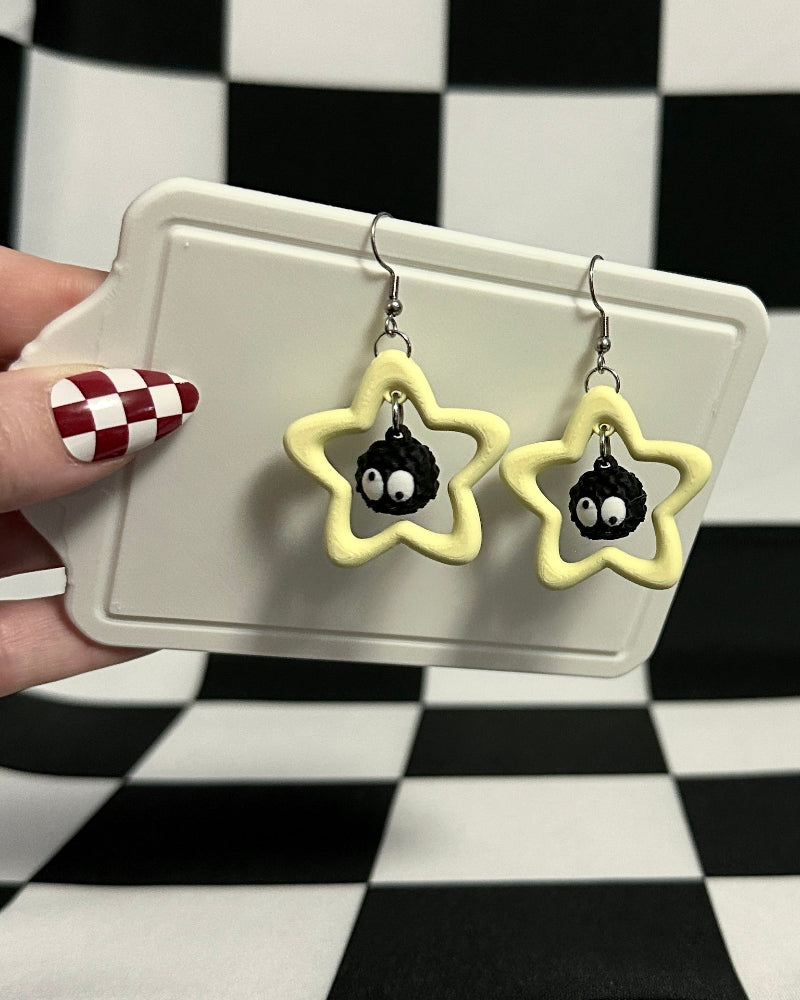 Star-shaped earrings on a card held against a checkered background