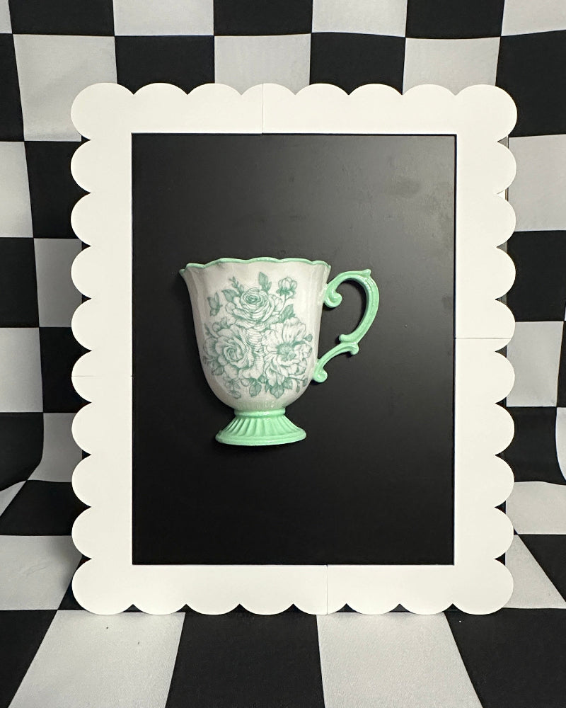 Green ceramic cup in a white frame on a black and white checkered background