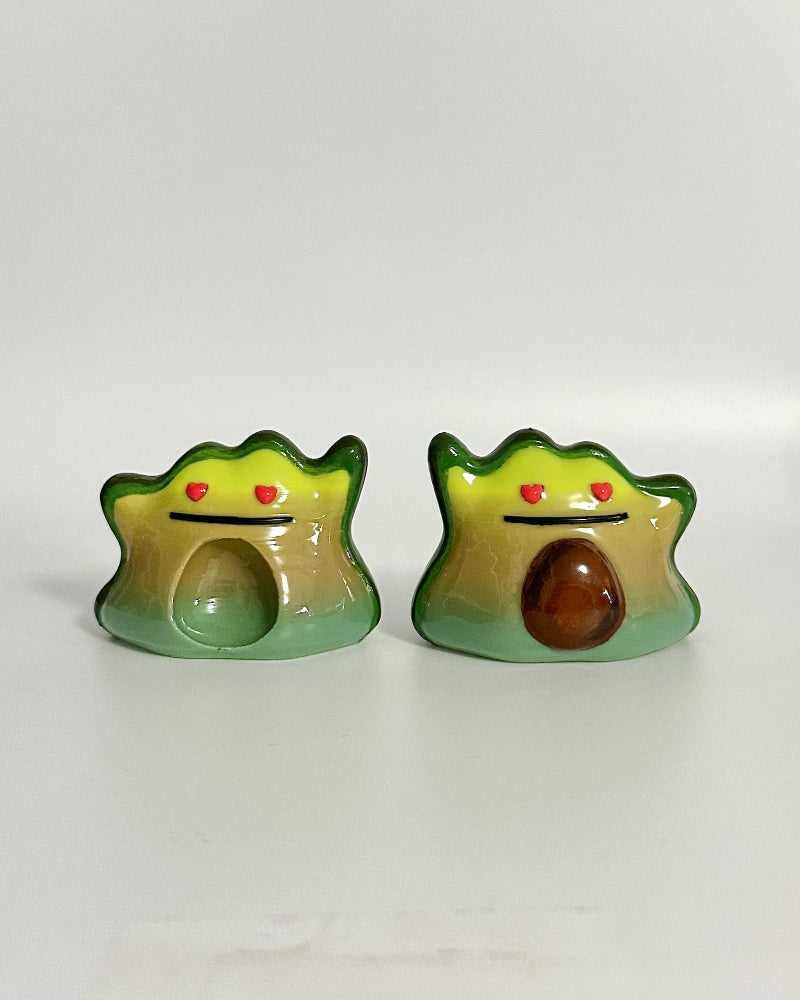 Two avocado-shaped items on a white surface with a blurred background.