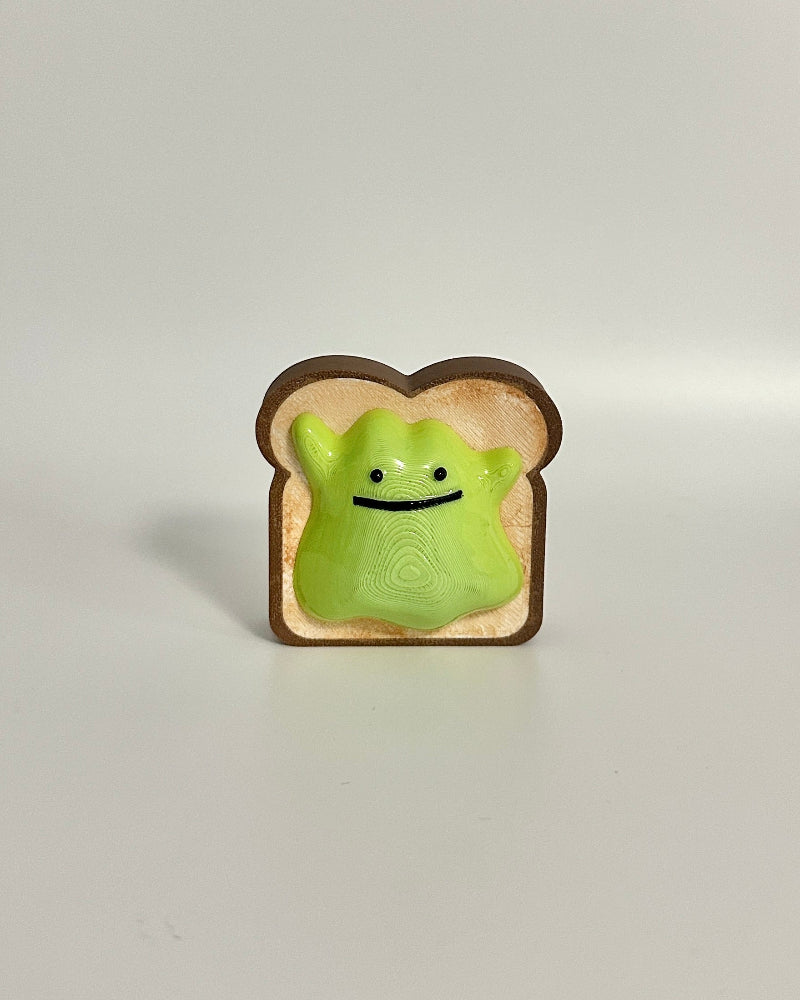 Small green avocado ditto on a slice of bread against a white background