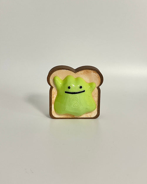 Small green avocado ditto on a slice of bread against a white background