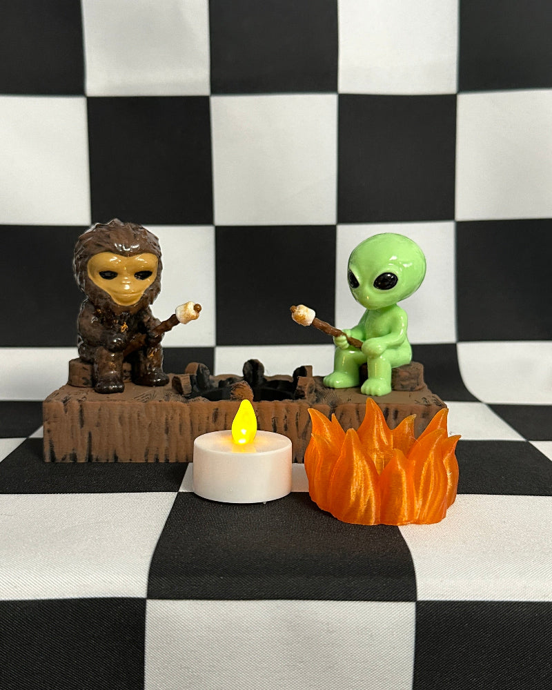 Two figurines by a small fire on a black and white checkered background