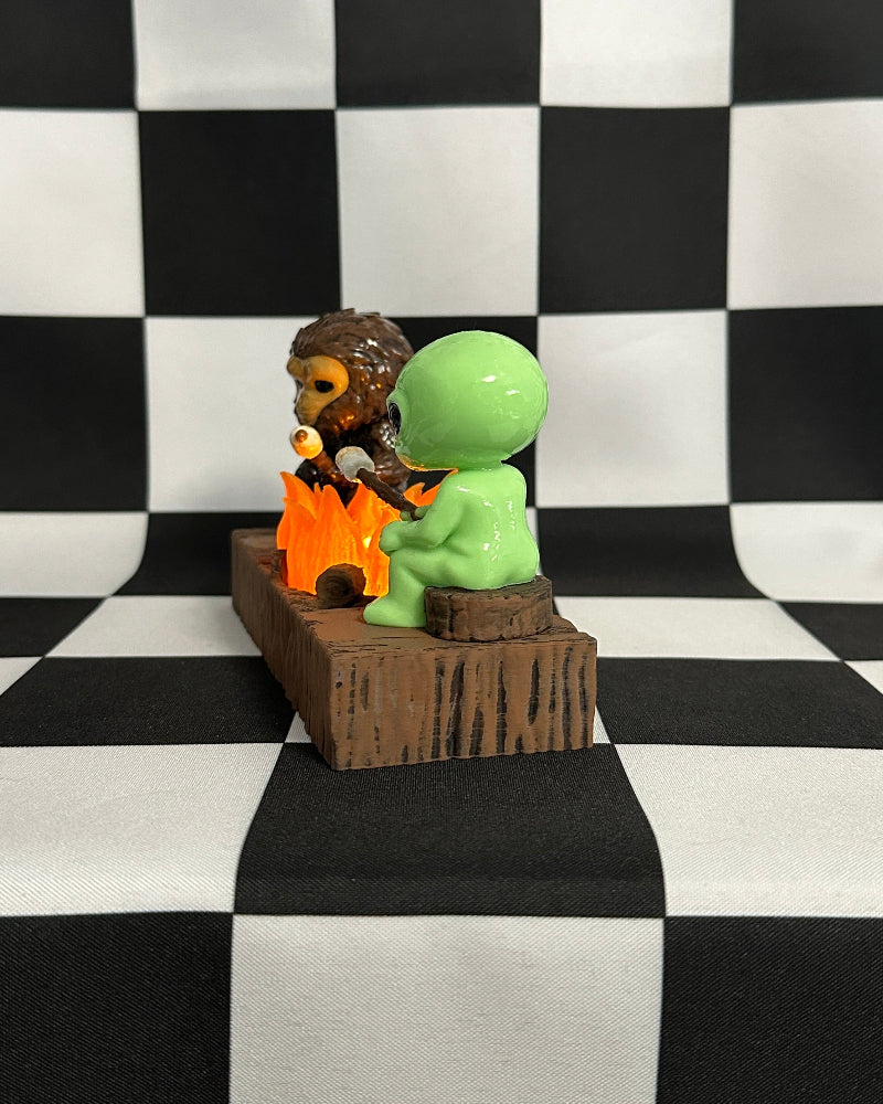 Two figurines on a small wooden platform against a black and white checkered background
