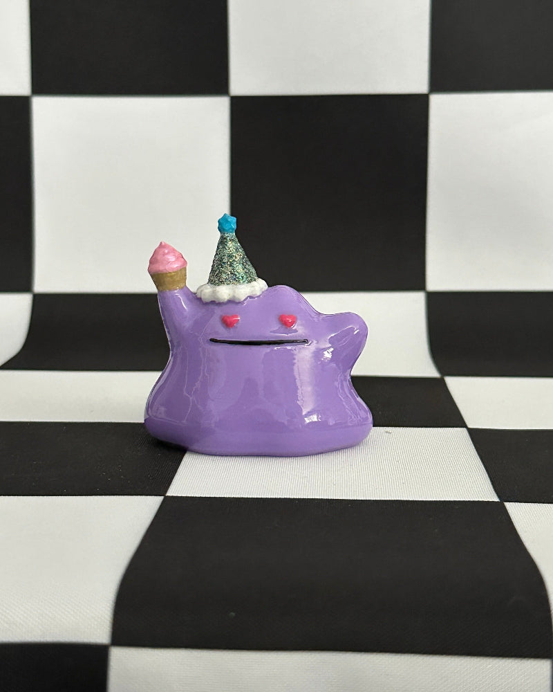 Purple monster-shaped piggy bank with small ice cream cones on a black and white checkered background