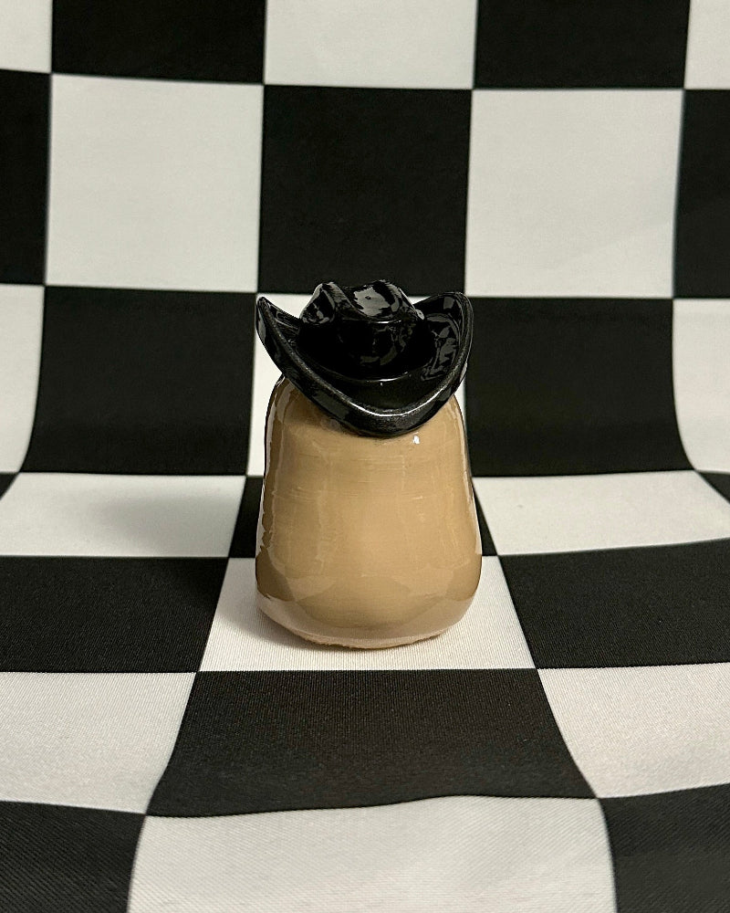 Tan capybara with black hat on a black and white checkered background