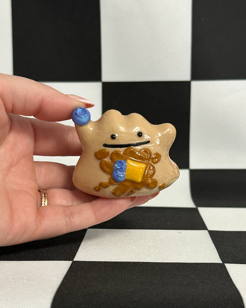 Hand holding a small star-shaped figurine with a checkered background