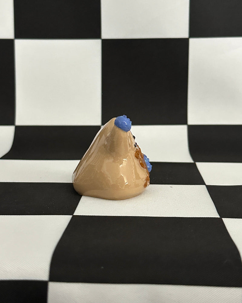 Small beige ceramic mountain with blue accents on a black and white checkered background