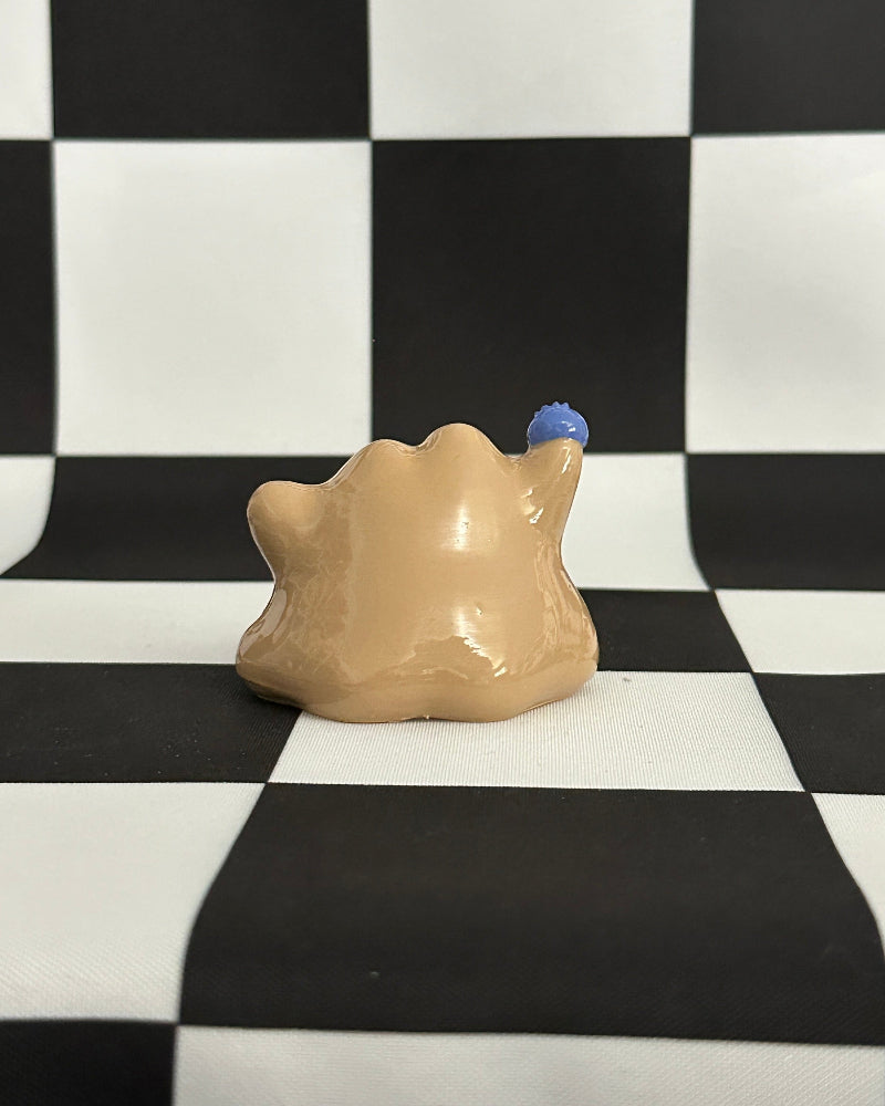 Beige ceramic object with blue accents on a black and white checkered background