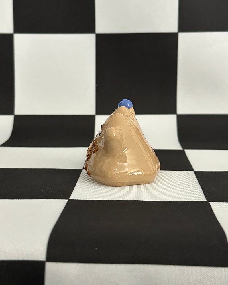 Beige ear model with blue cap on a black and white checkered background