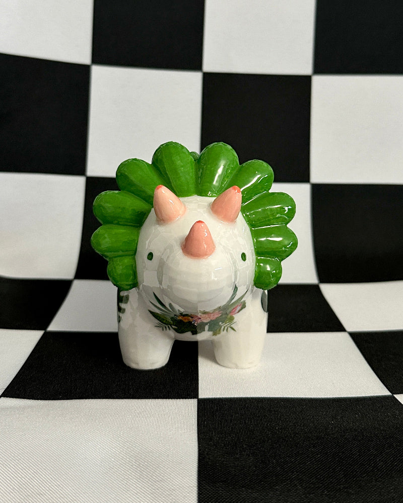 Small figurine with a green spiky hairstyle on a black and white checkered background