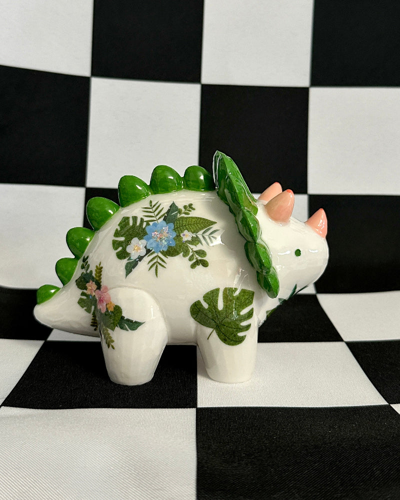 Decorative dinosaur figurine with floral patterns on a black and white checkered background