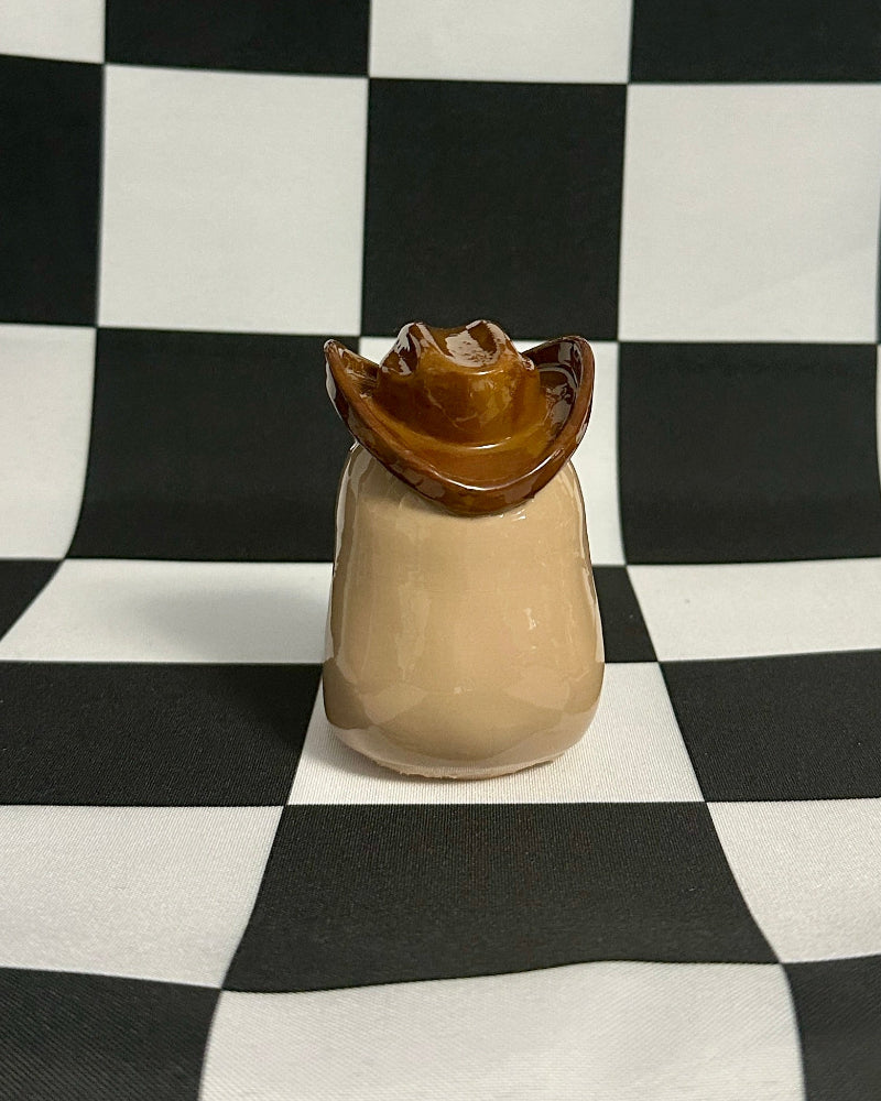 Small figurine with a hat on a black and white checkered background
