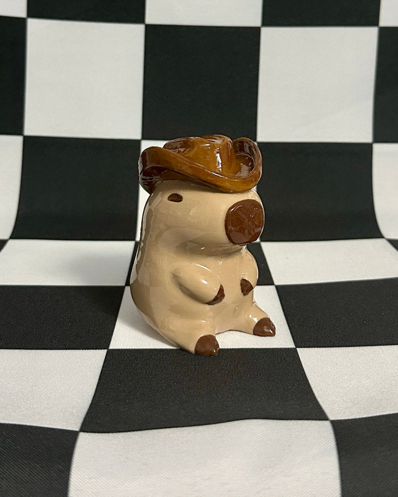 Small animal figurine with a hat on a black and white checkered background