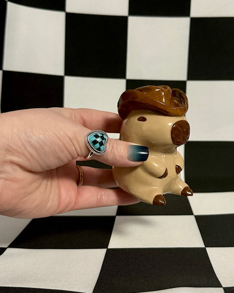 Hand holding a small figurine against a black and white checkered background