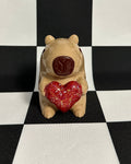 Small capybara figurine with a red heart on a black and white checkered background