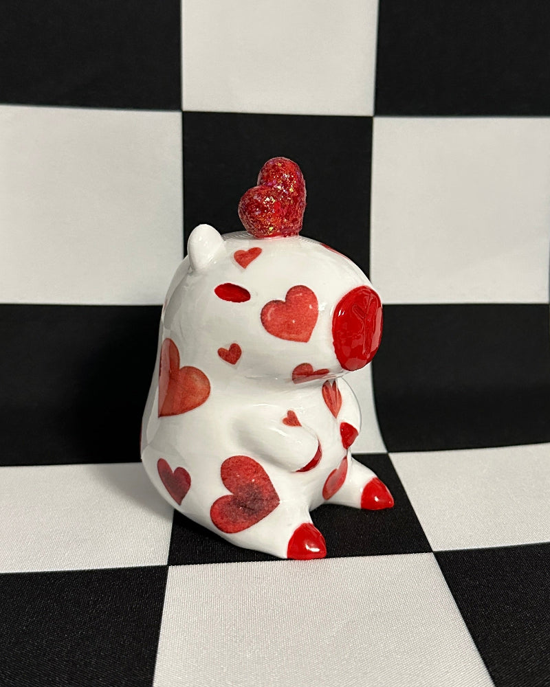 White figurine with red heart patterns on a black and white checkered background