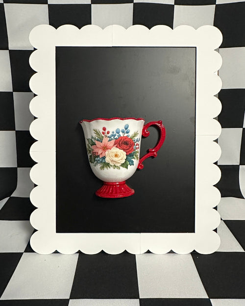 Decorative teacup with floral design on a black background framed by a white scalloped border against a black and white checkered pattern.