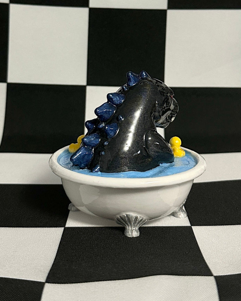 Black and blue creature figure on a white pedestal against a black and white checkered background