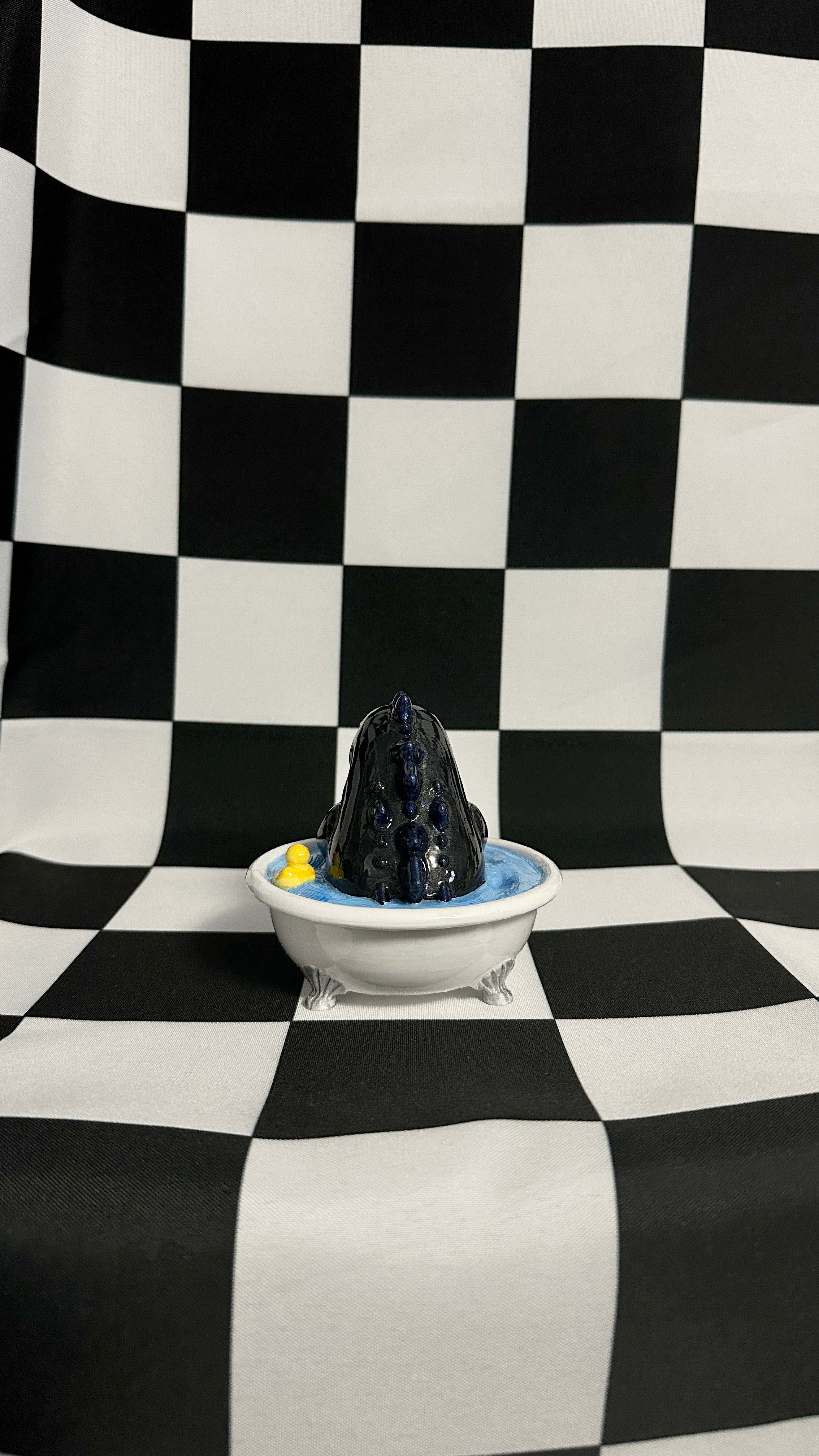 Black volcanic sculpture in a white bowl on a checkered black and white background