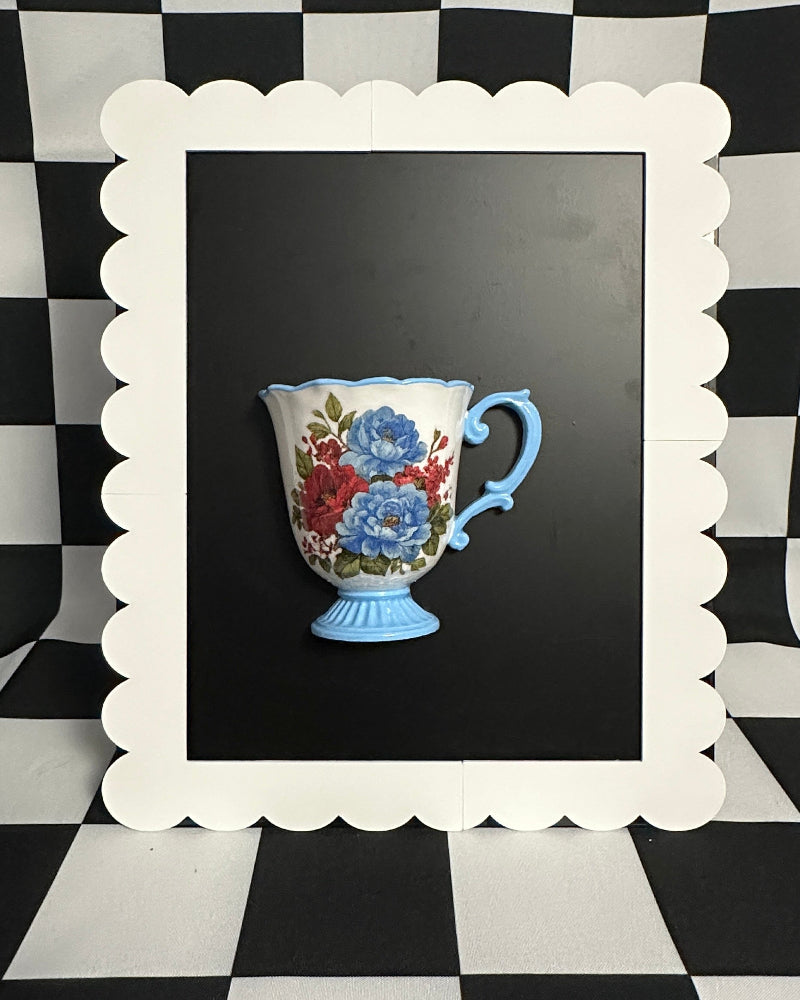 Decorative teacup with floral design in a white frame against a black and white checkered background