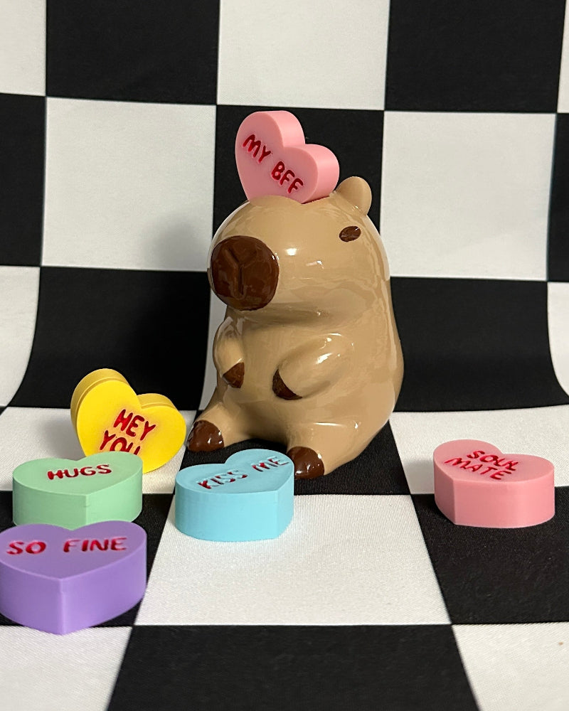 capybara figurine with heart-shaped candies on a checkered background