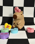capybara figurine with heart-shaped candies on a checkered background