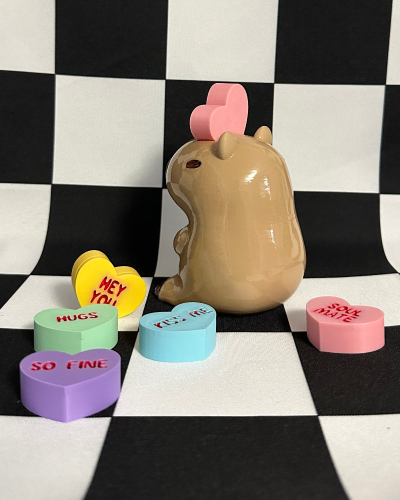 Stylized capybara figurine with heart-shaped ears on a checkered black and white background