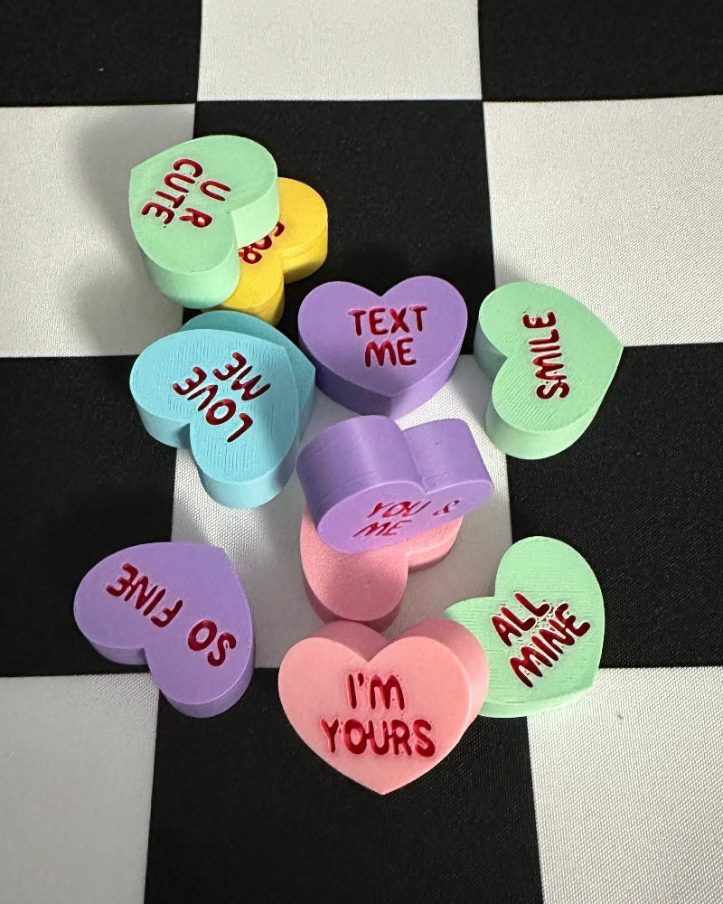 Colorful candy hearts with text on a black and white checkered background