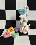 dog figurine with colorful heart-shaped accessories on a black and white checkered background