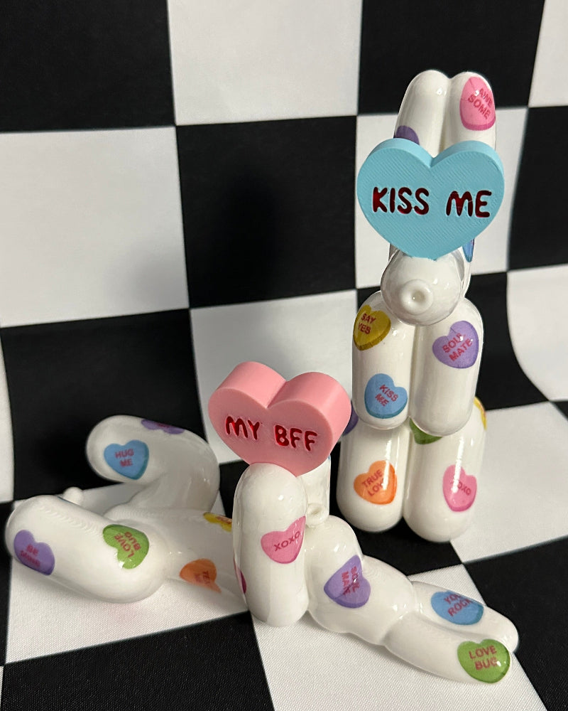 White ceramic dog figurine with heart-shaped text on a checkered background