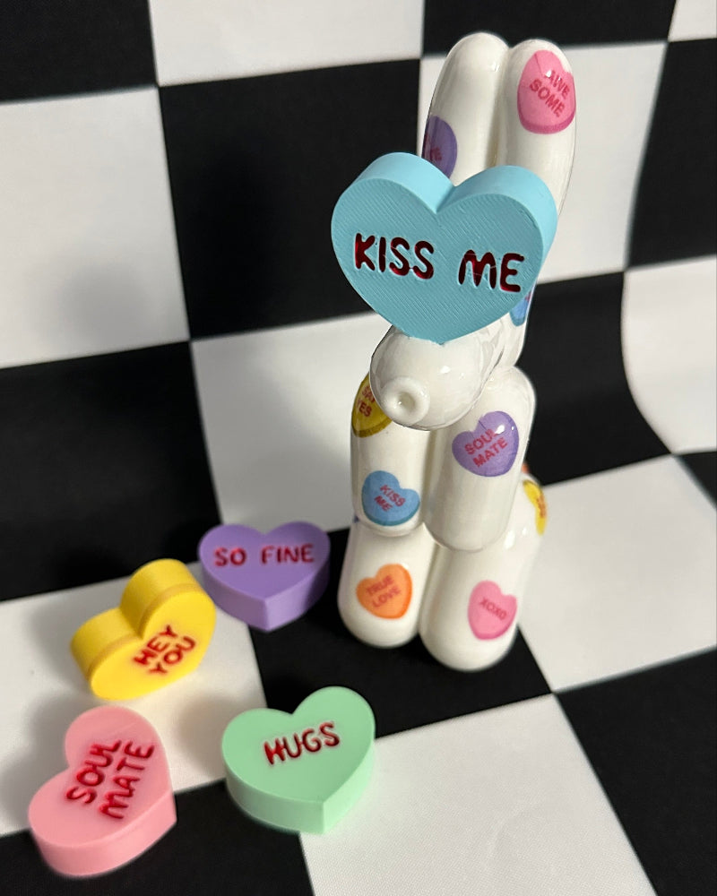 White dog figurine with colorful heart-shaped candies on a black and white checkered background