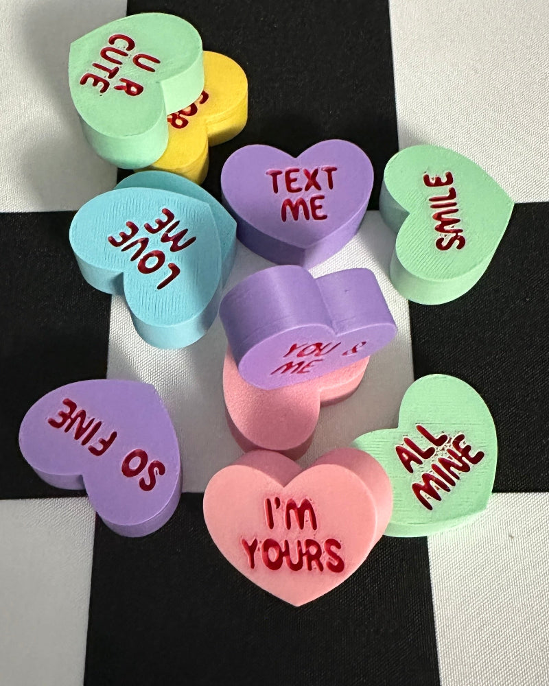 Colorful candy hearts with text on a black and white checkered background