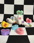 Colorful candy hearts with various messages on a checkered background