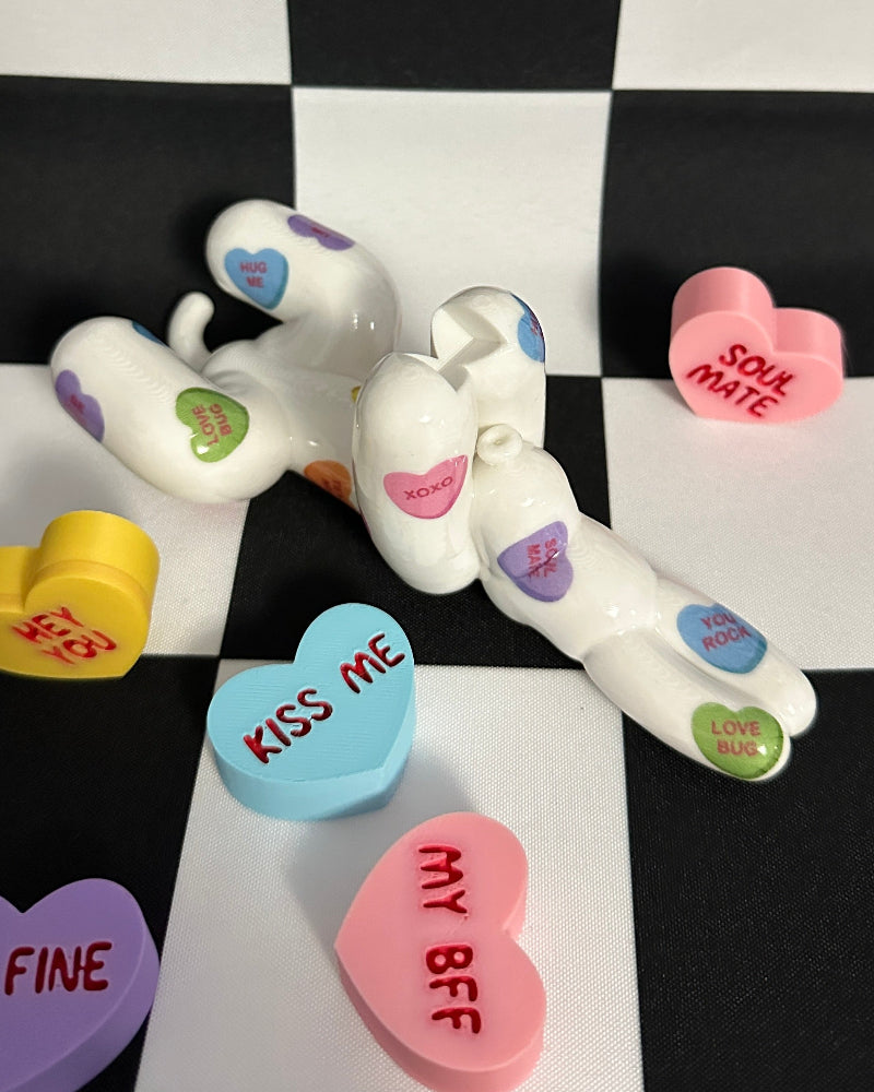 Decorative items resembling conversation hearts and a small figurine on a checkered background