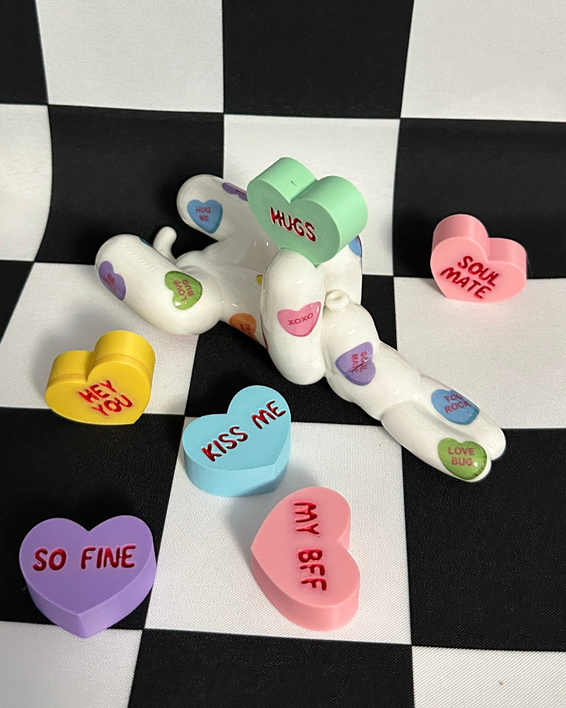 Decorative heart-shaped tokens with colorful text on a black and white checkered background