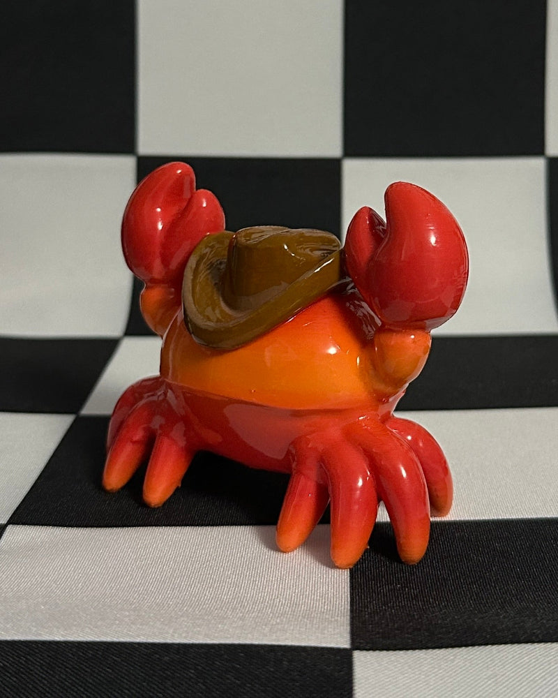 Red crab figurine with a yellow shell on a black and white checkered background