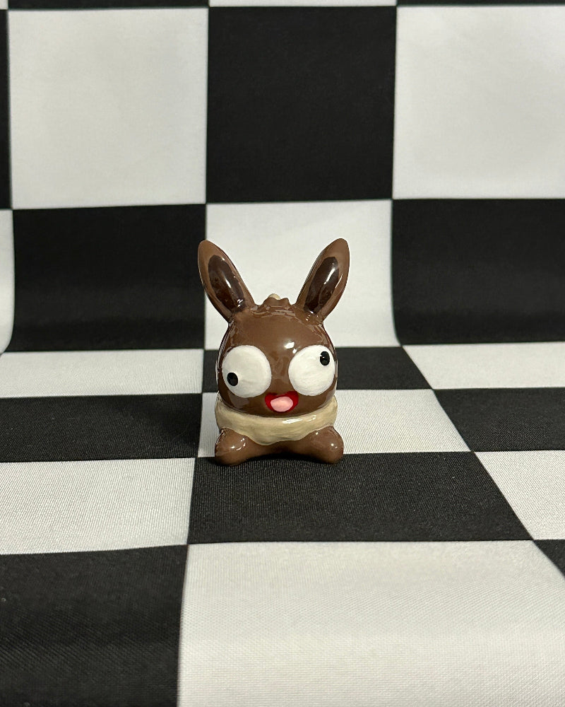 Small brown and white figurine on a black and white checkered background