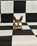 Small brown and white figurine on a black and white checkered background