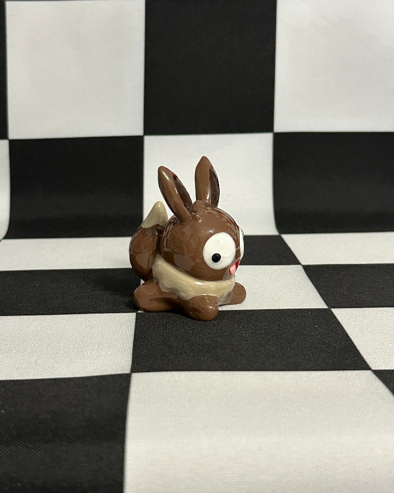 Small brown rabbit figurine on a black and white checkered background