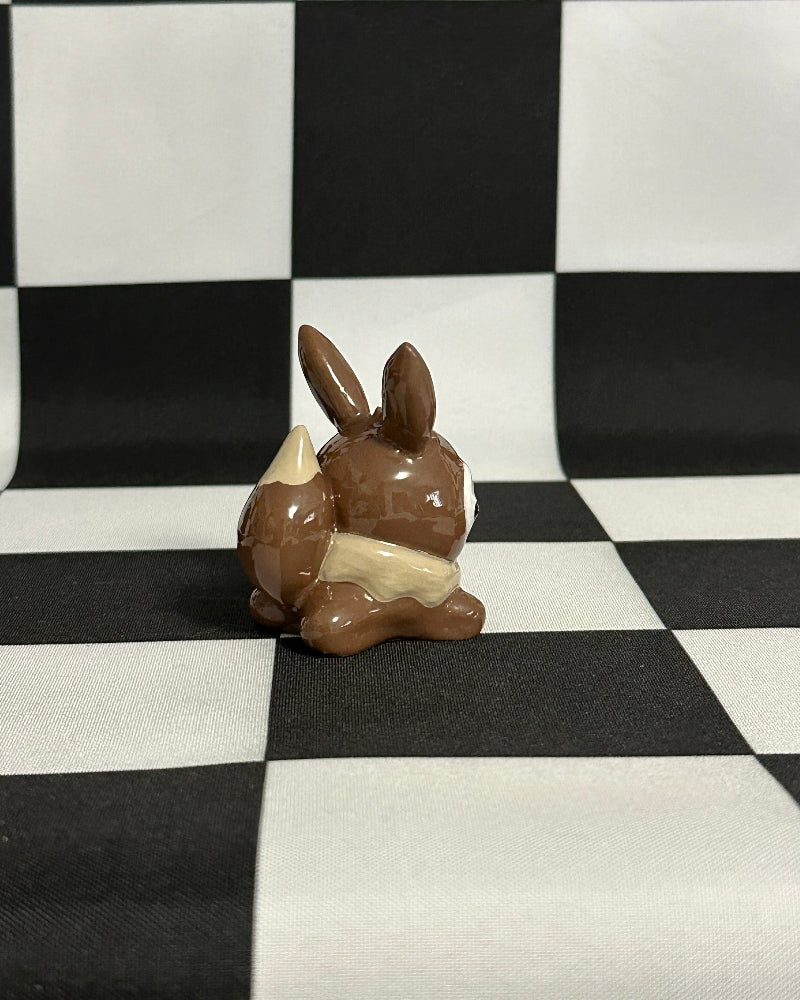 Small chocolate bunny on a black and white checkered background